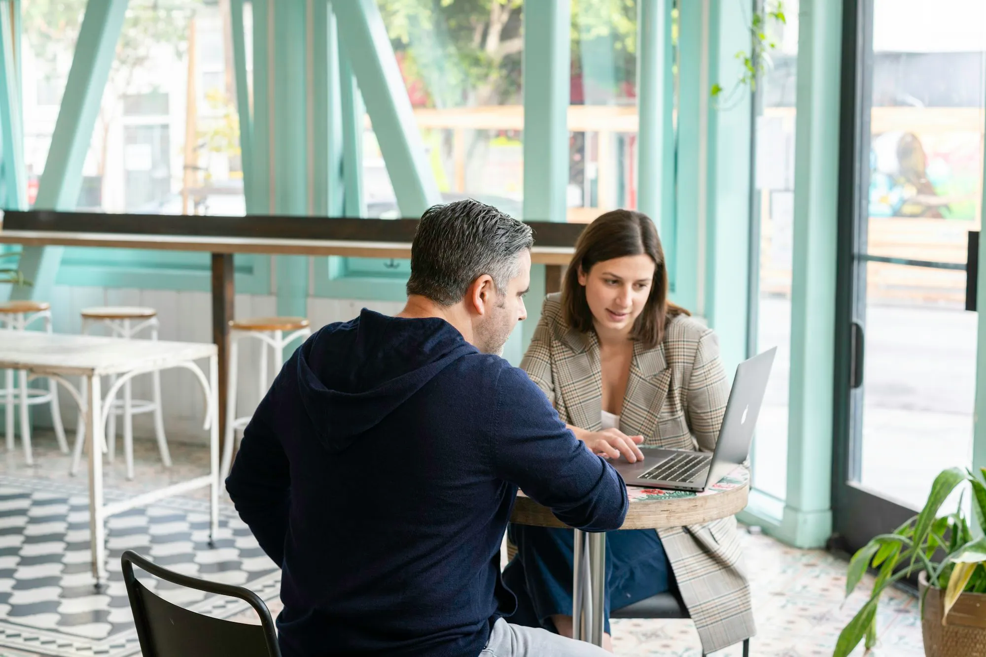 Empresária e desenvolvedor conversando sobre um sistema de gestão no notebook