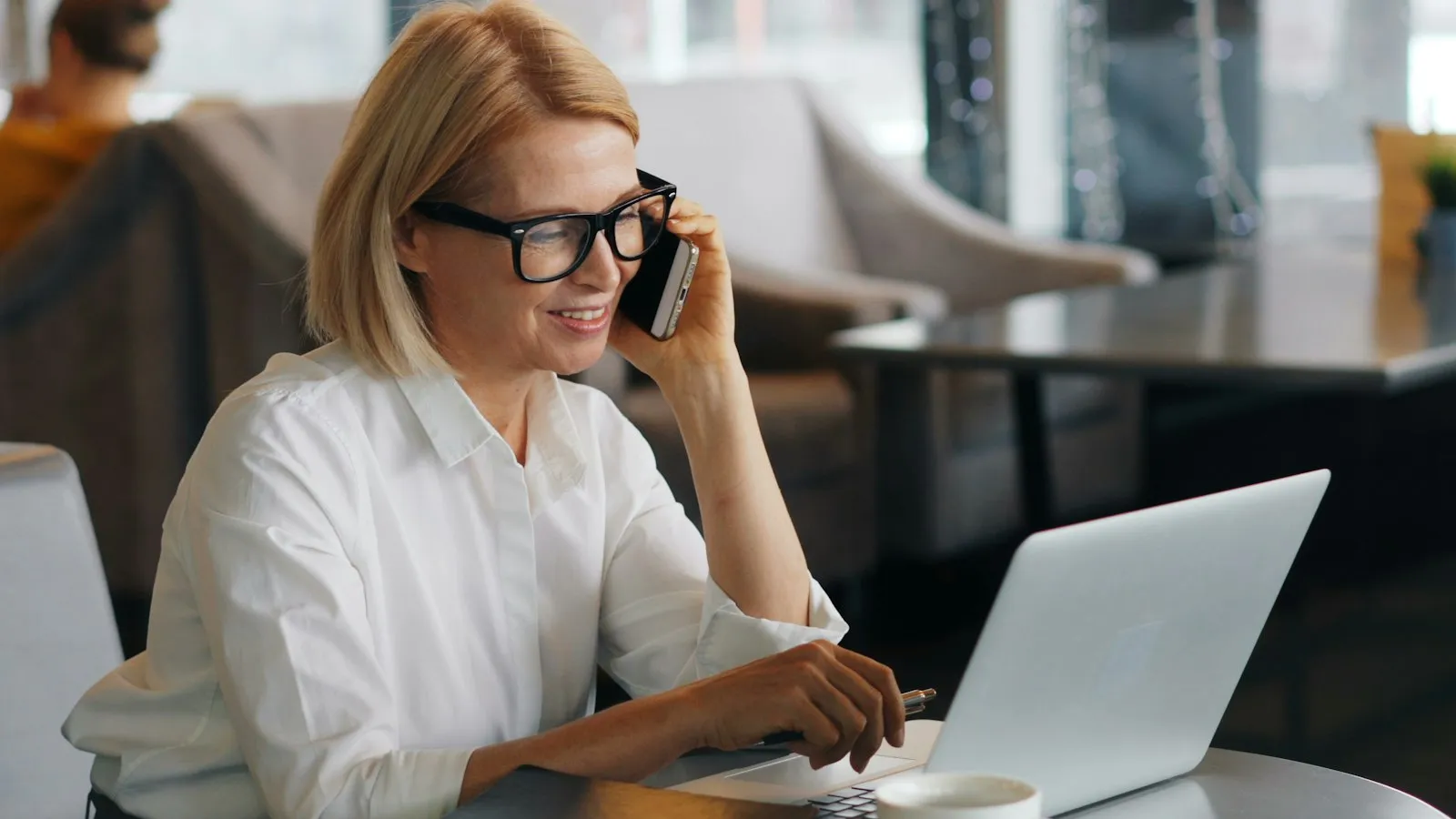 Recepcionista de clínica conferindo a agenda no computador enquanto atende o telefone